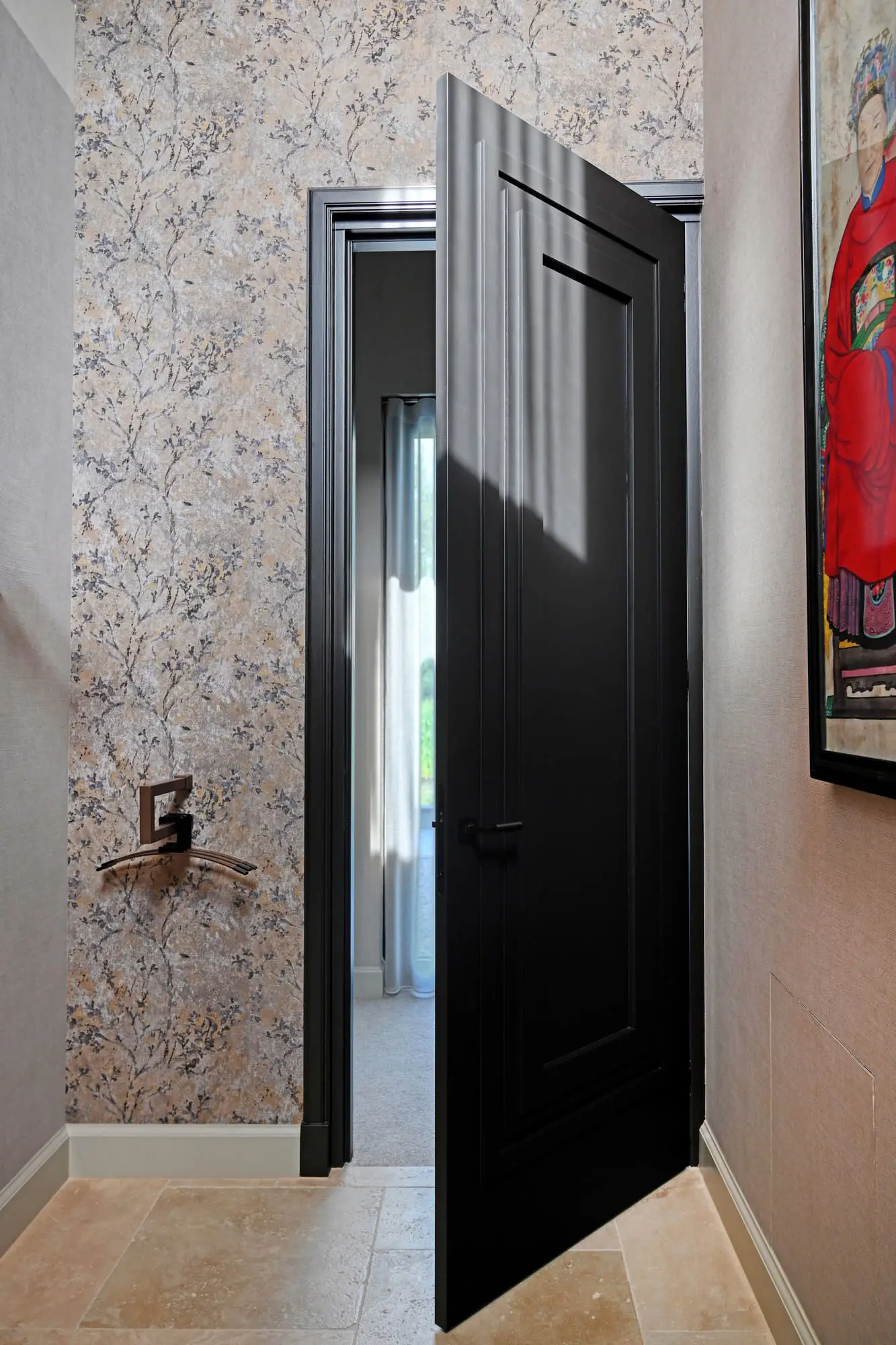 Zwart gelakte paneeldeur met zwart kozijn in een hal met bloesembehang op de wand