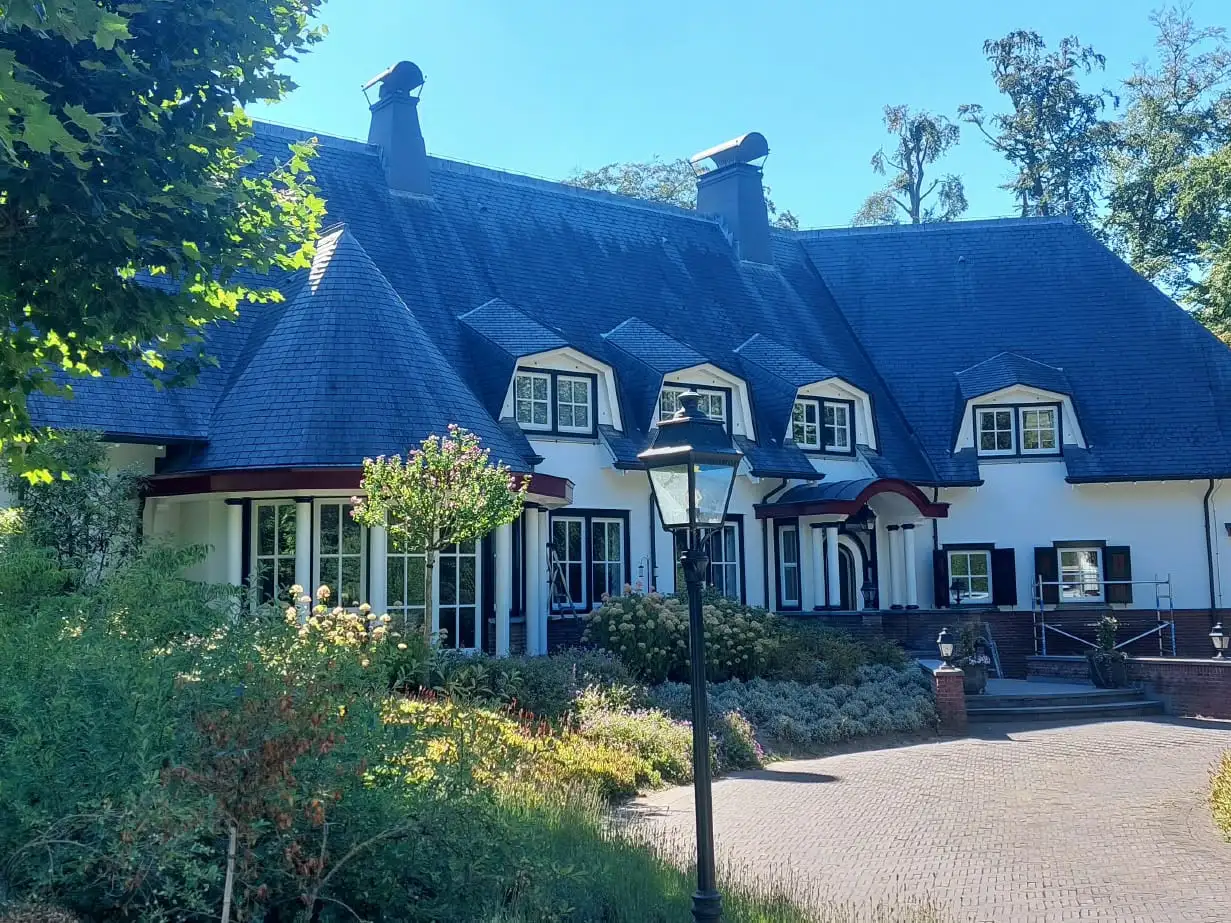 Wit geschilderde villa met dakkapellen en donkere kozijnen, na buitenschilderwerk